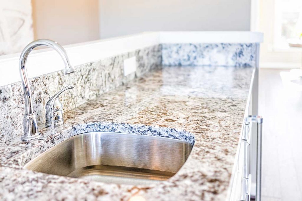 New Modern Faucet And Kitchen Sink Closeup With Granite Countertops
